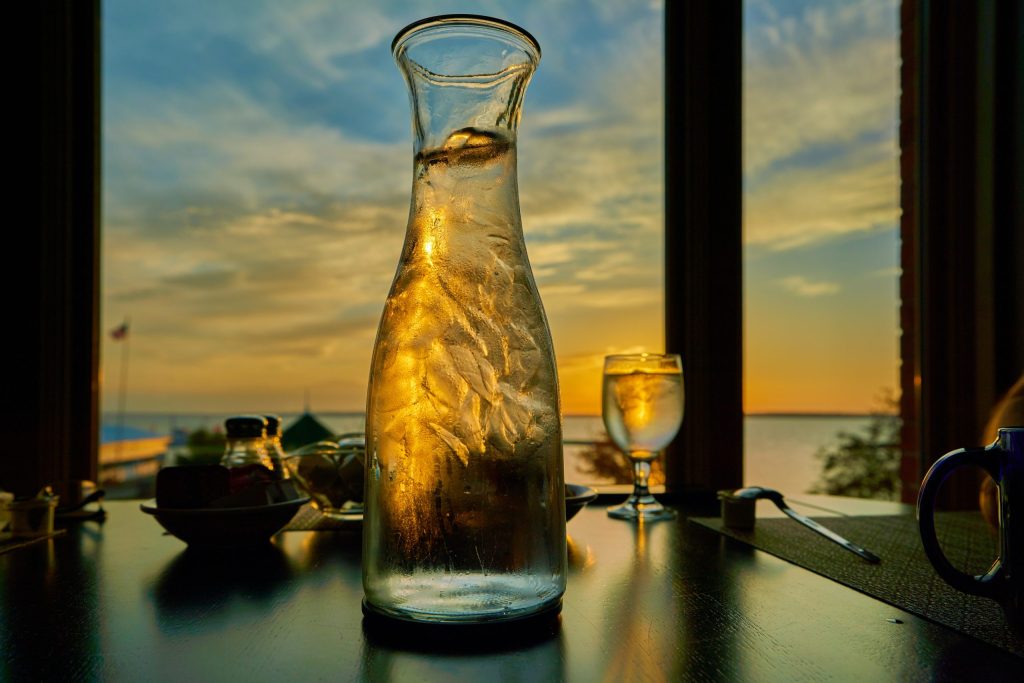 A bottle of water on a table in front of a window.