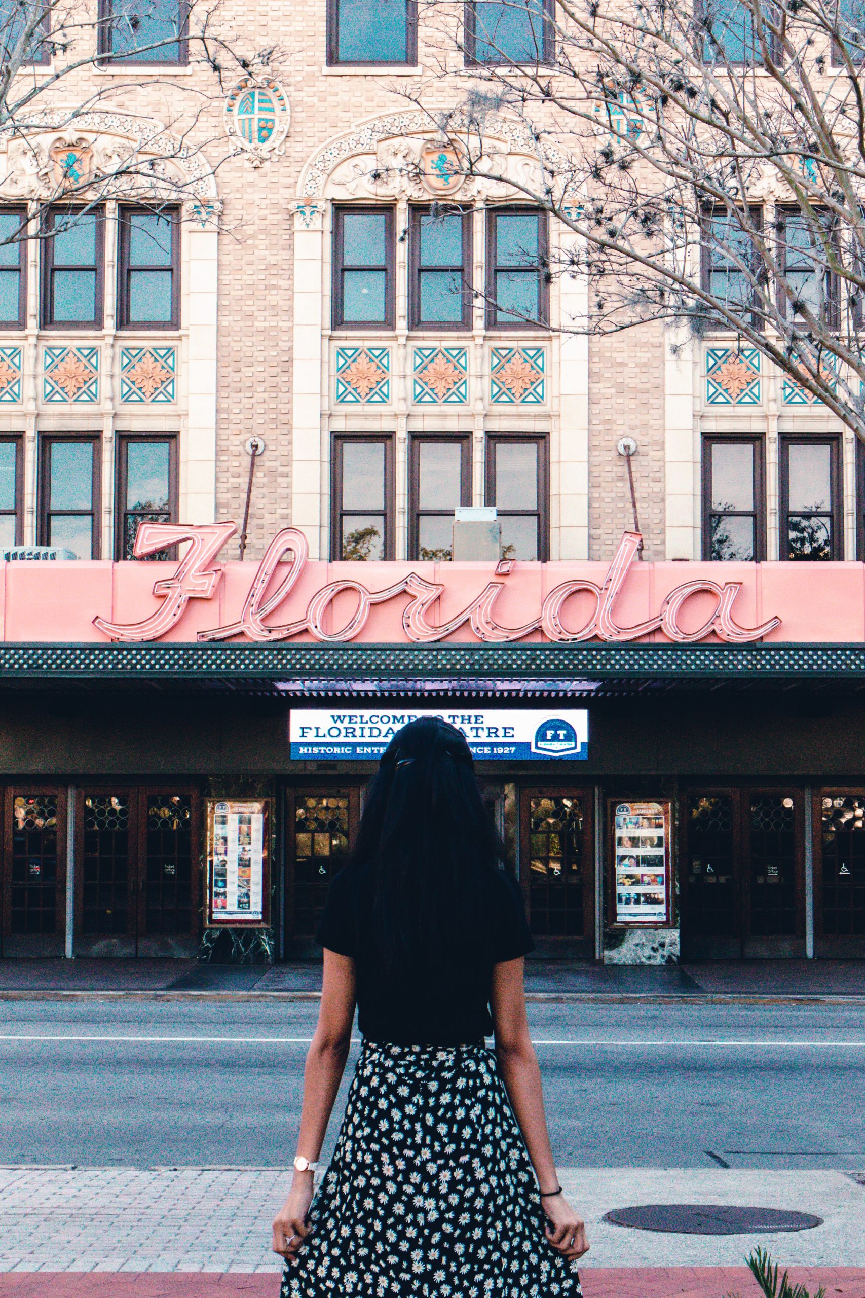 A woman in a polka dot dress standing in front of a theater.