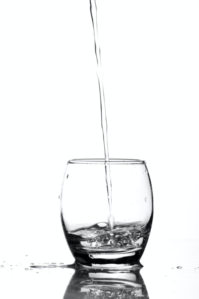 A glass of water is being poured into a glass.