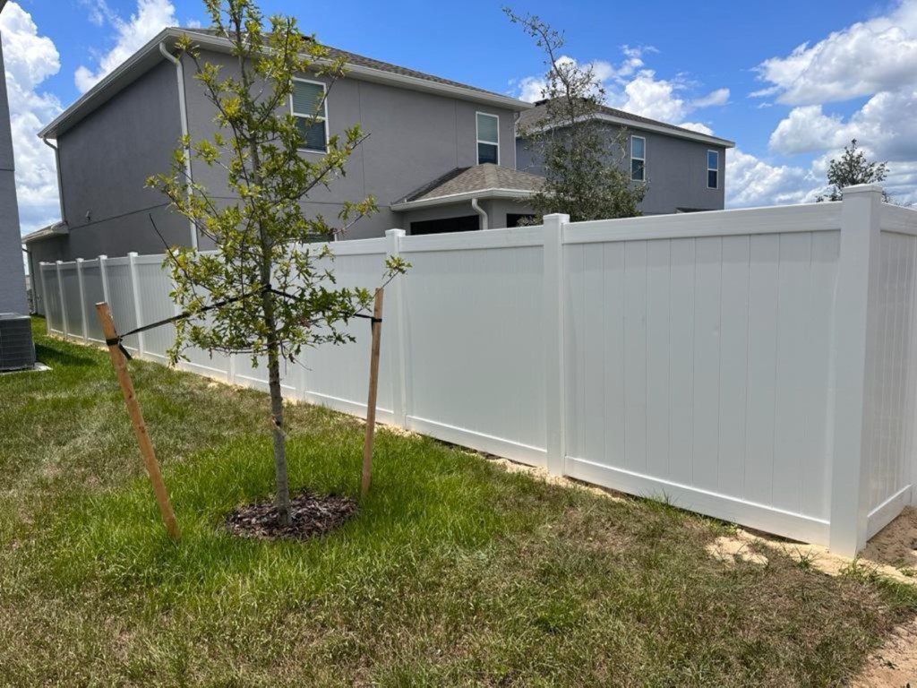 A white fence with a tree in front of it, fencing