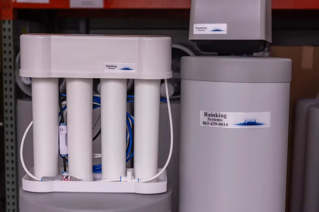 Water filtration and softening system with labeled units and visible tubes in a storage area.