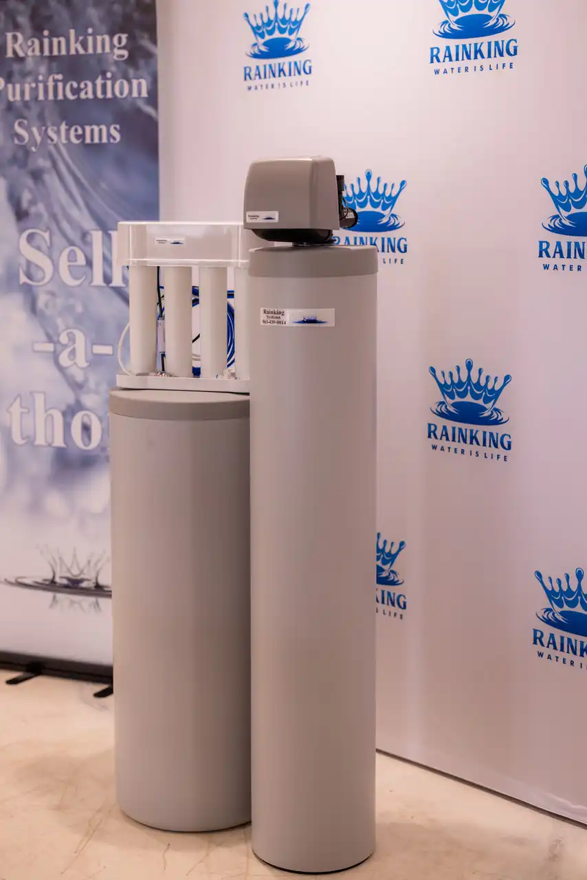 Two cylindrical water purification systems displayed in front of a backdrop with "Rainking Water is Life" logos.