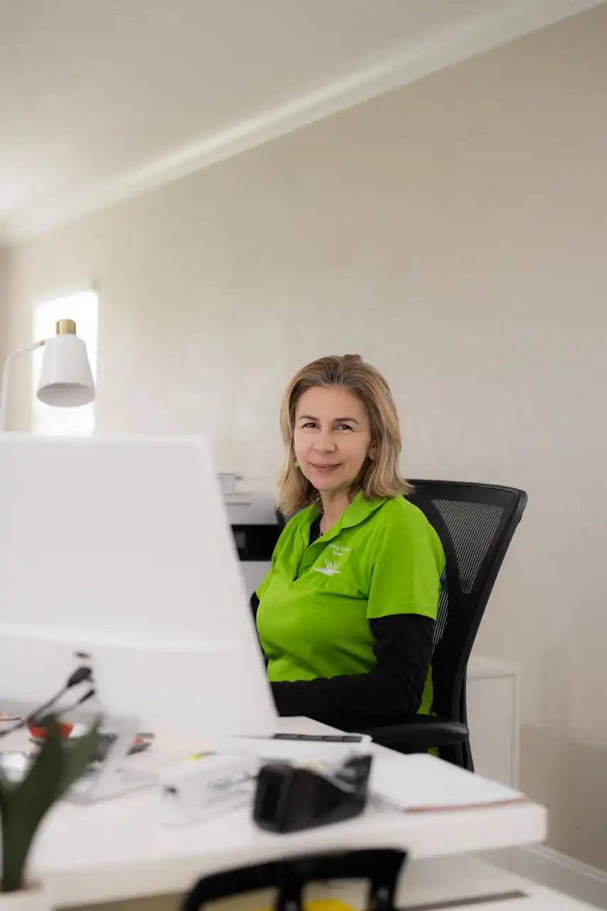 A woman in a green shirt sitting at a desk.